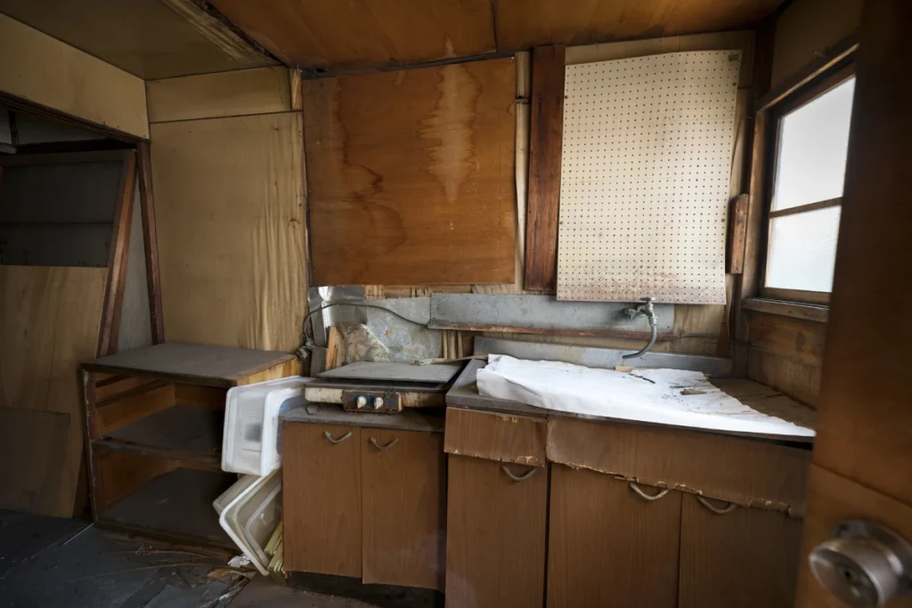 Alte, verschlissene Einbauküche mit Holzschränken und Spüle vor dem Küche abbauen